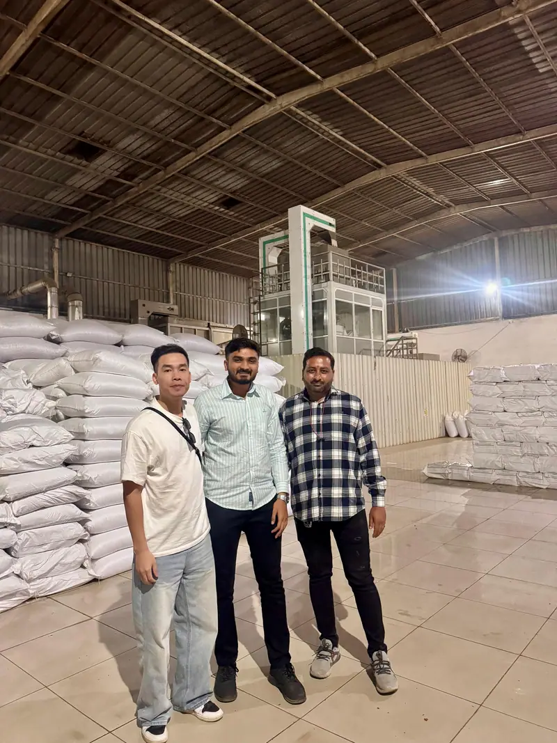 Visitors at a warehouse with stacked export bags