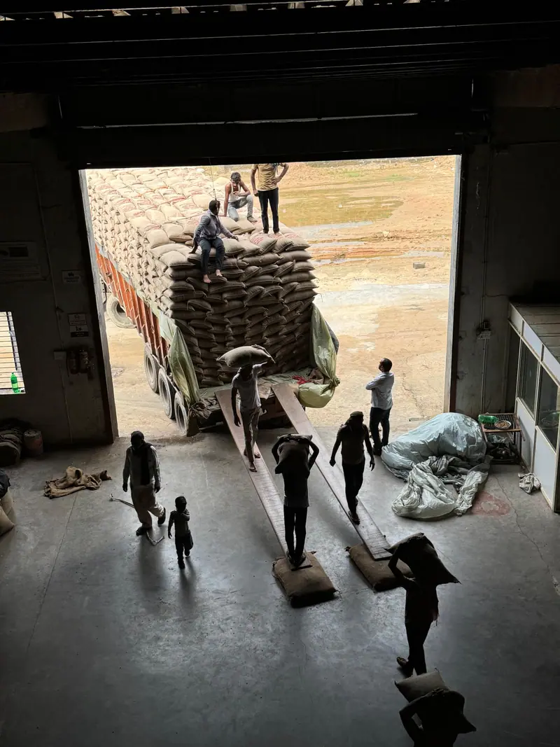 Workers carrying bags between a truck and the warehouse