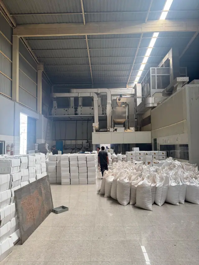Export cartons and filled woven bags in the packing hall, below the cleaning and grading plant