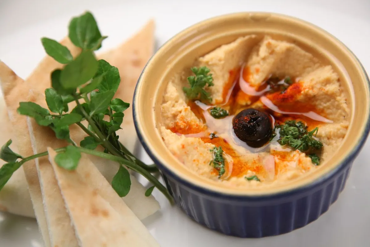 Bowl of hummus made with sesame tahini and flatbread