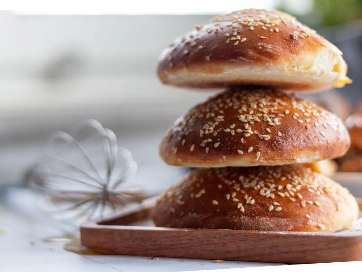 Stack of sesame seed buns on a wooden tray
