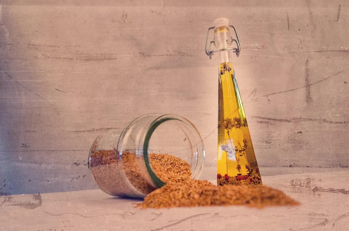 Sesame seeds for oil next to a bottle of sesame oil