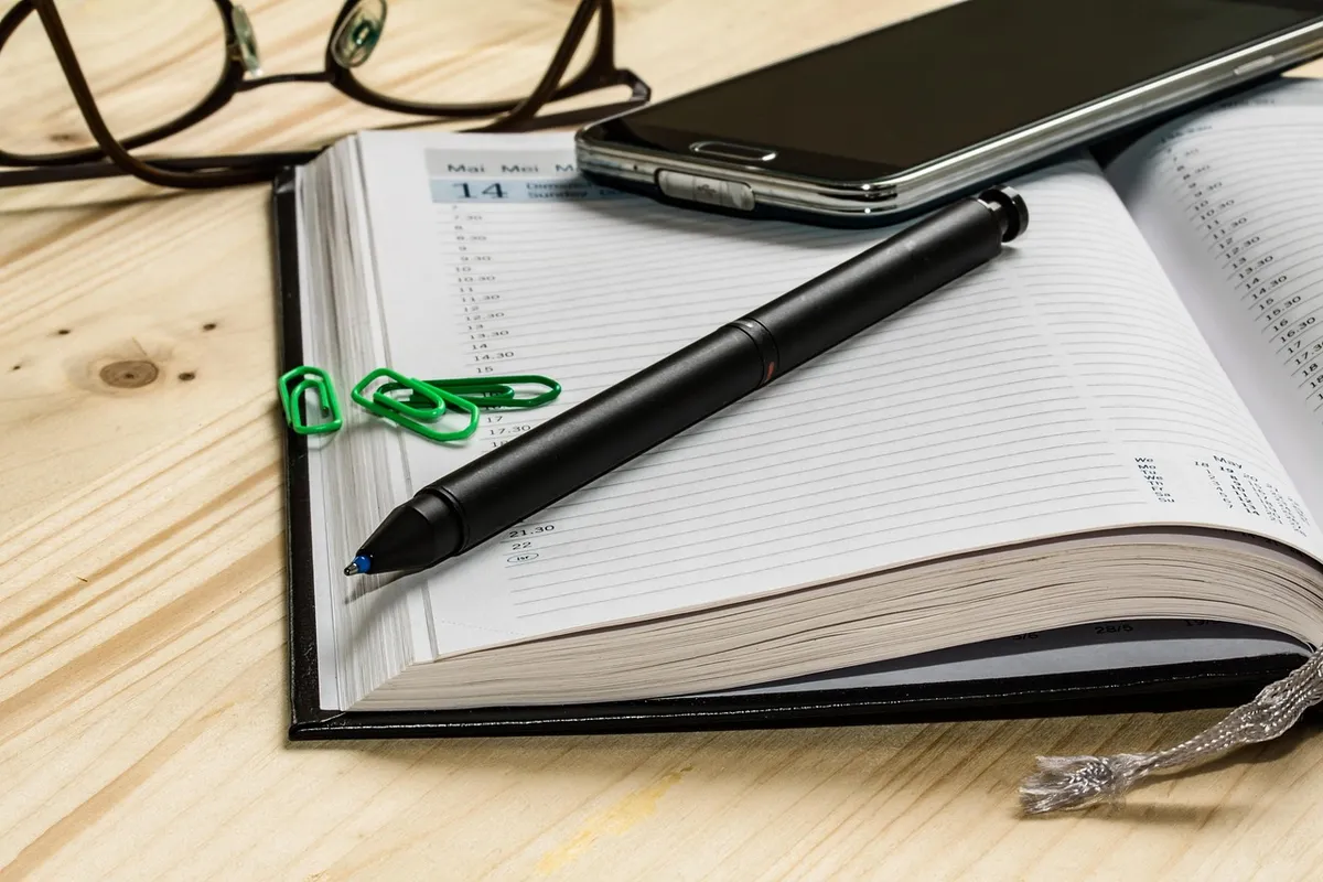 Diary and pen for recording trade show meeting notes and follow-up actions